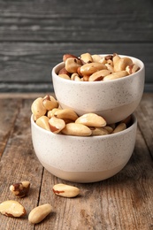 Bowls with tasty Brazil nuts on wooden table