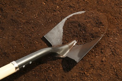 Photo of Metal shovel on fertile soil. Gardening tool