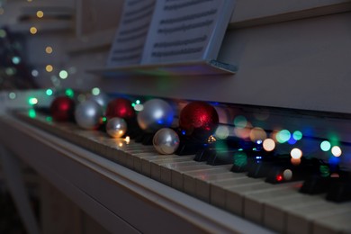 Photo of Festive decor on piano keys indoors, closeup. Christmas music