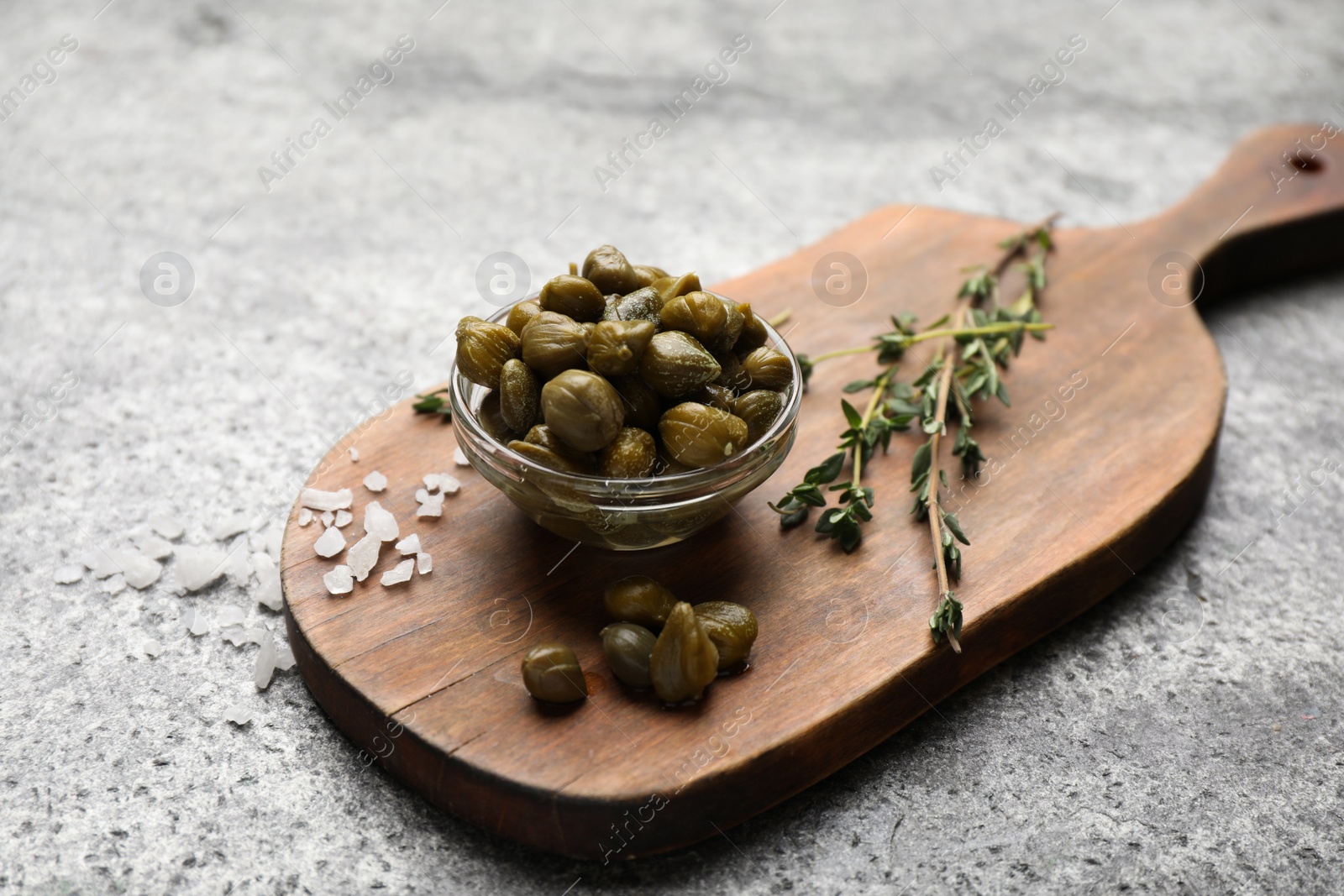 Photo of Tasty capers, salt and thyme on grey table