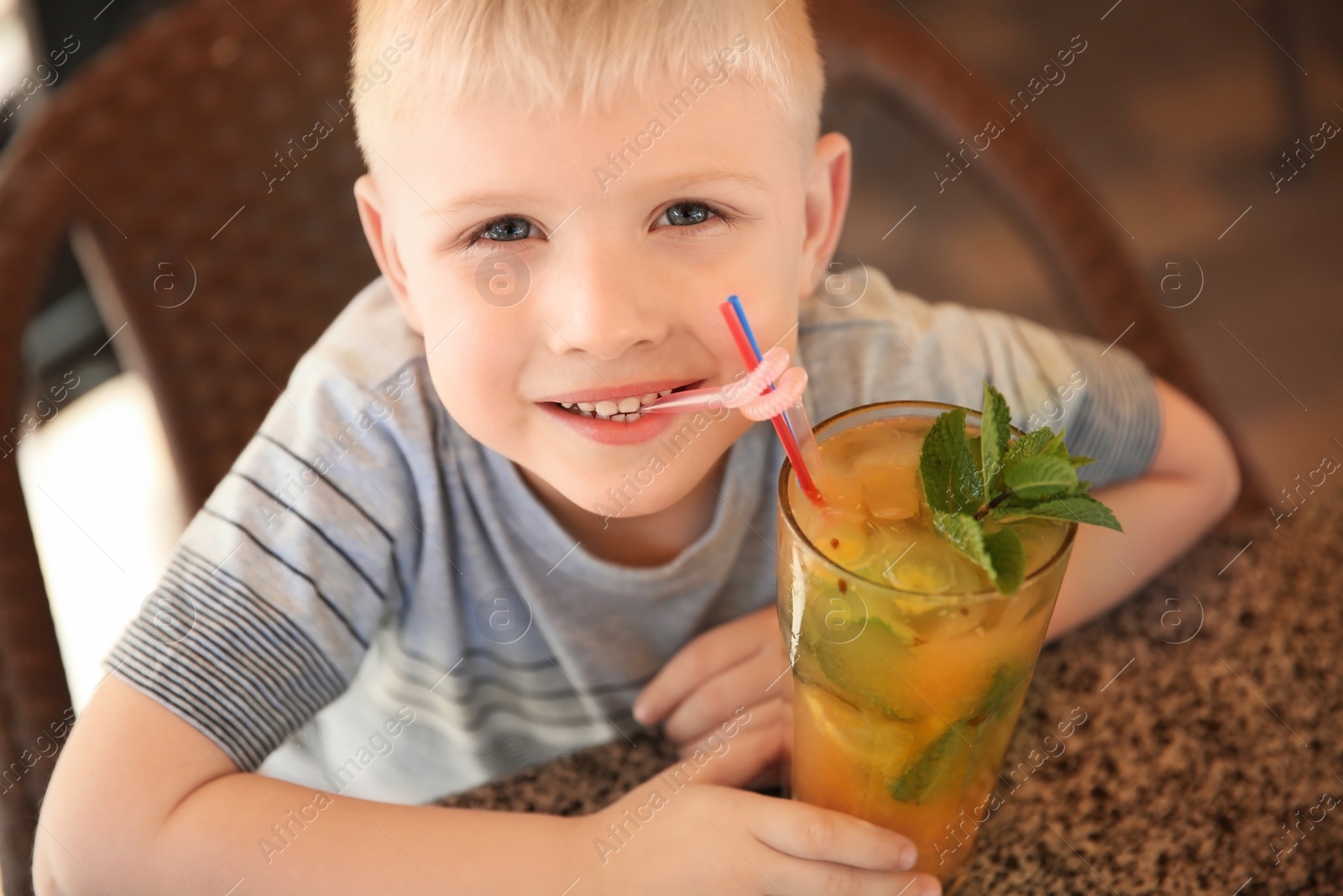 Photo of Cute boy with glass of natural lemonade at table in cafe