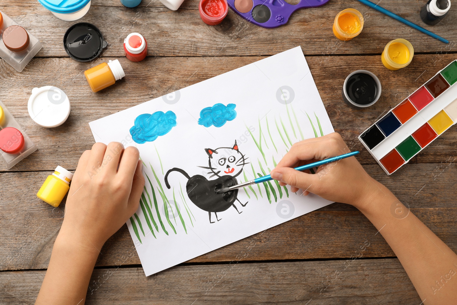 Photo of Girl painting picture of cat on table, top view