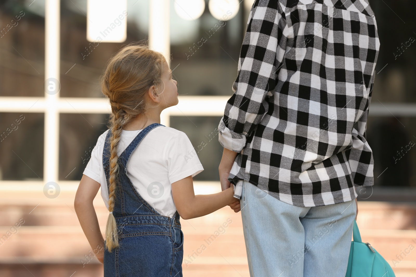 Photo of Little girl with her mother near school, back view