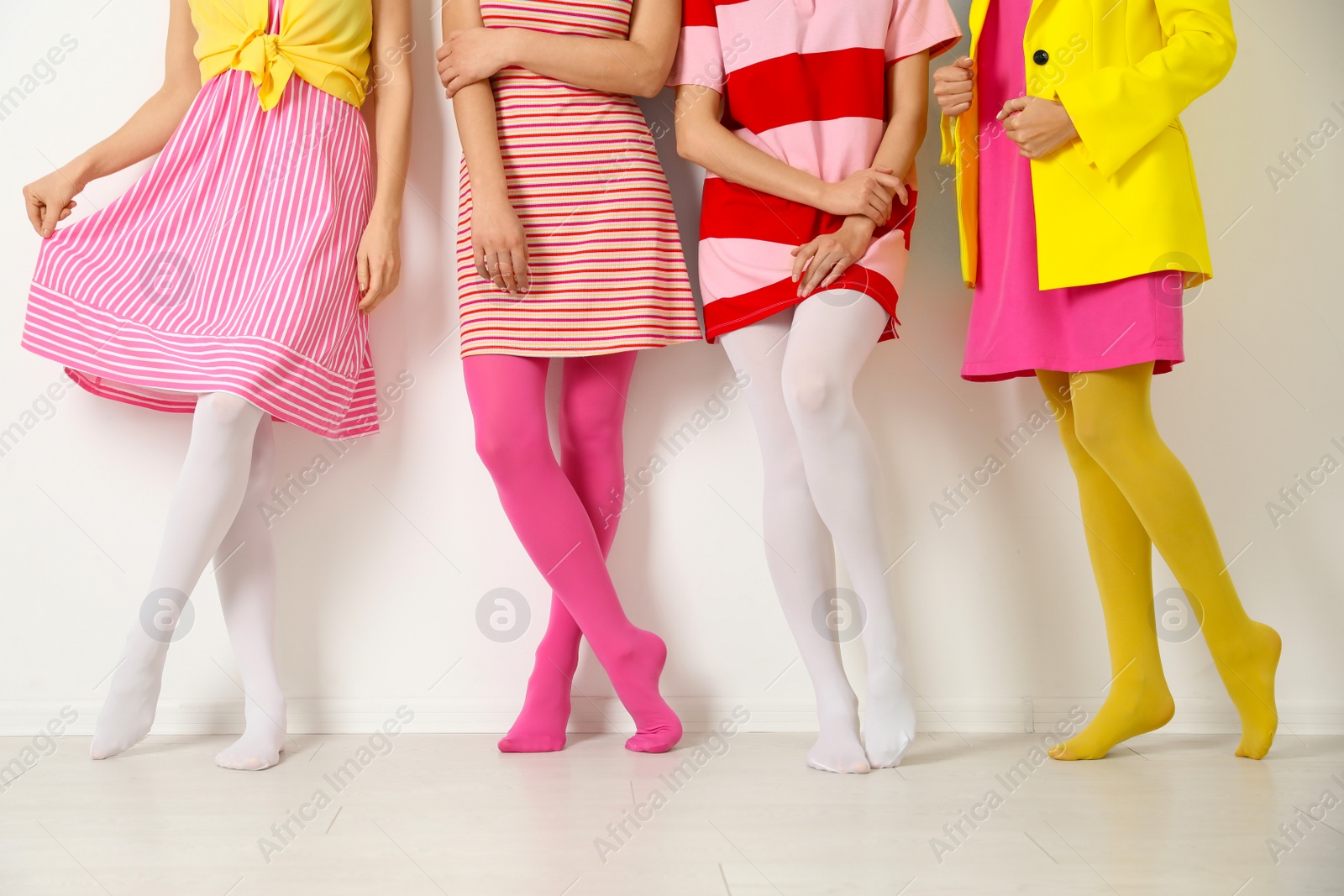 Photo of Women wearing colorful tights near white wall, closeup