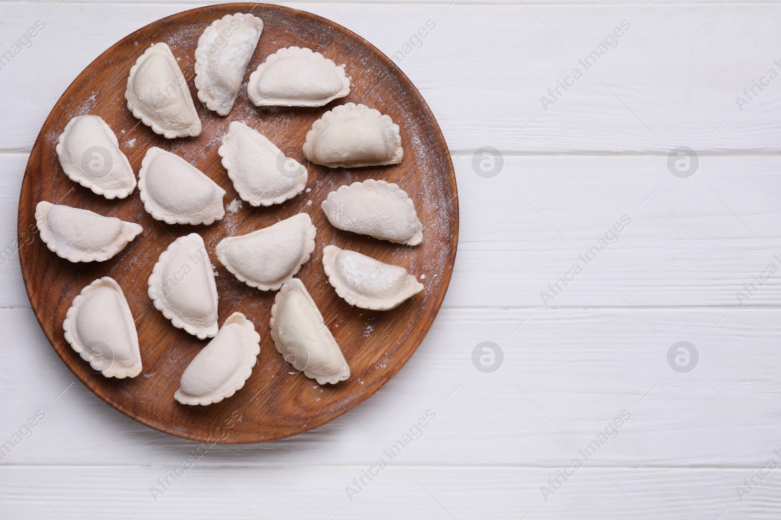 Photo of Raw dumplings (varenyky) on white wooden table, top view. Space for text