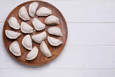 Photo of Raw dumplings (varenyky) on white wooden table, top view. Space for text