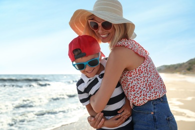 Photo of Happy mother and son on sandy beach near sea. Family vacation