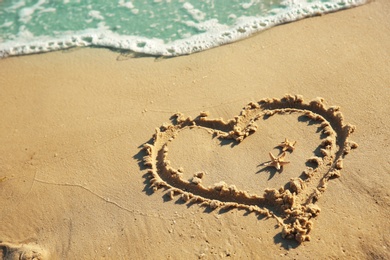 Photo of Heart drawn on sandy beach. Wedding concept
