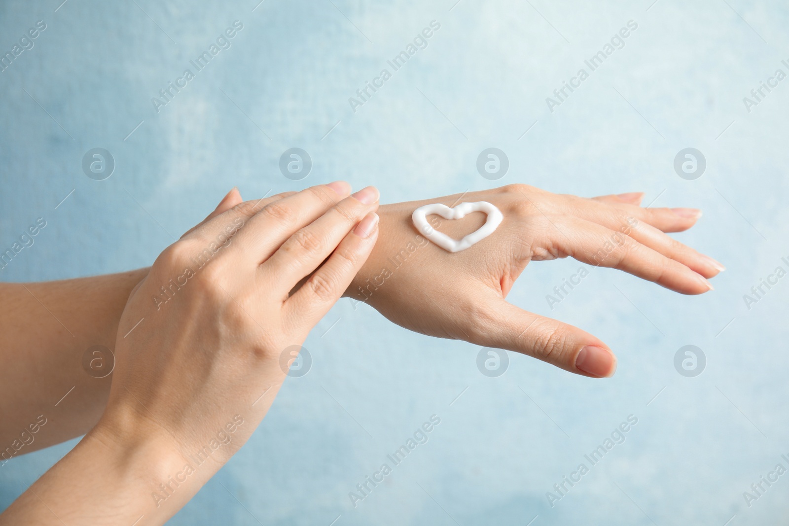 Photo of Woman applying hand cream on light background, closeup