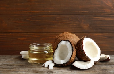 Jar of natural organic oil and coconuts on brown wooden table