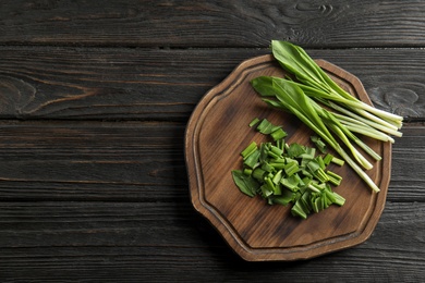 Board with wild garlic or ramson on wooden table, top view. Space for text