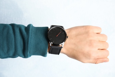 Man with stylish wrist watch on color background, closeup. Time management