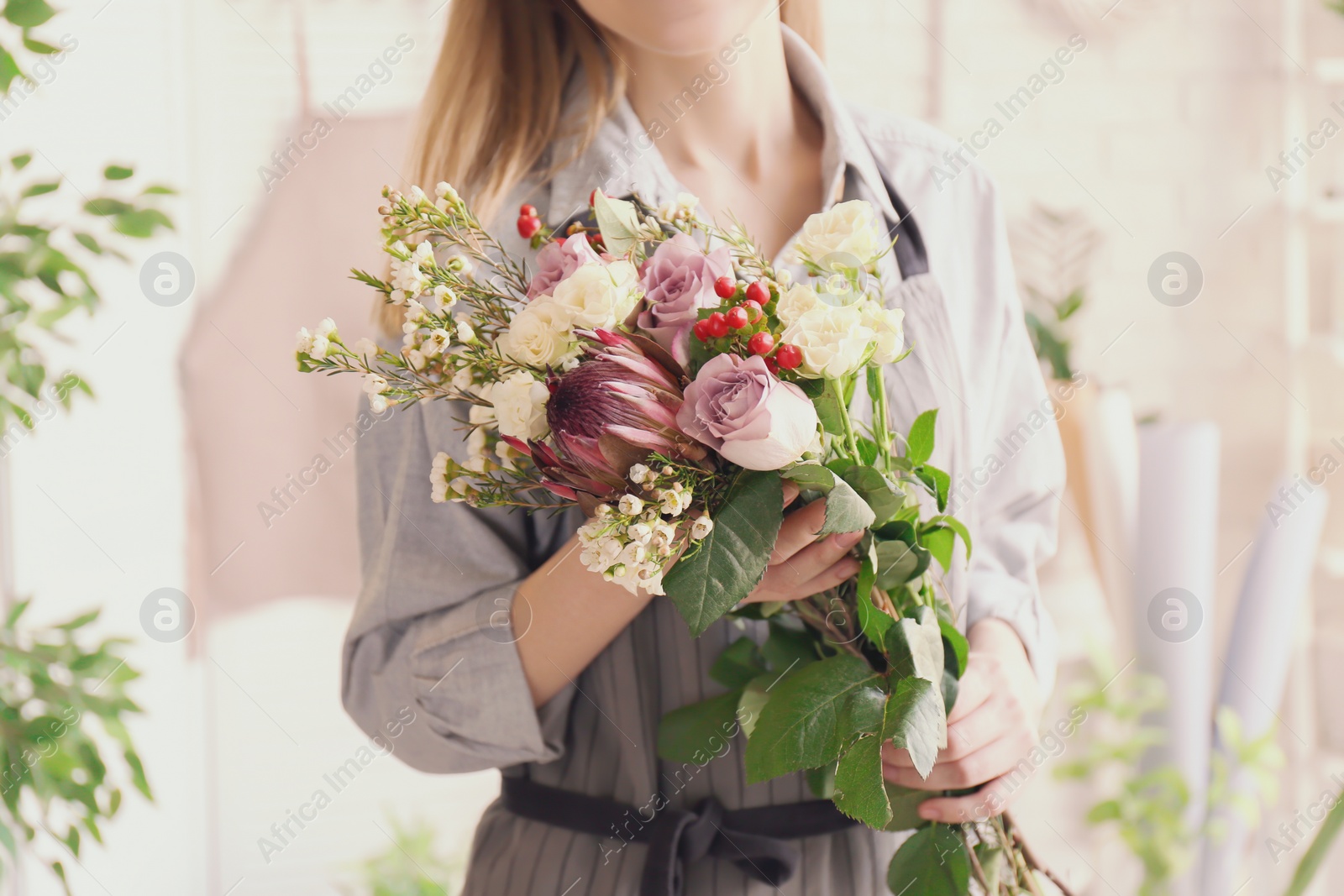 Photo of Female florist with beautiful bouquet at workplace