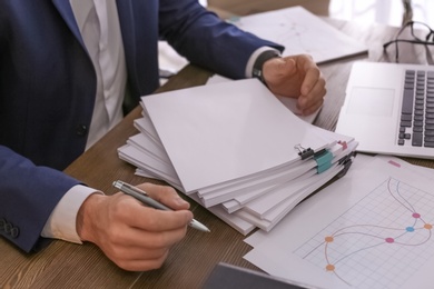 Photo of Businessman working with documents at office table, closeup. Space for text