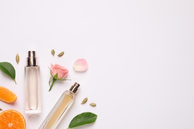 Photo of Flat lay composition with bottles of perfume, beautiful flower and tangerine on white background. Space for text