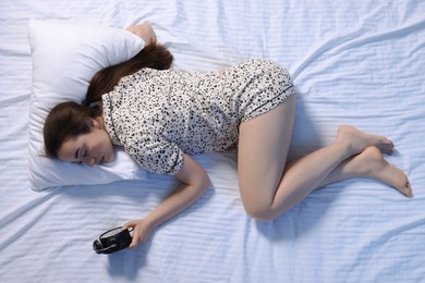 Photo of Woman looking at alarm clock on bed, top view. Insomnia problem