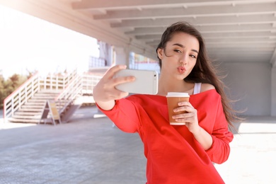 Photo of Attractive young woman taking selfie with phone outdoors