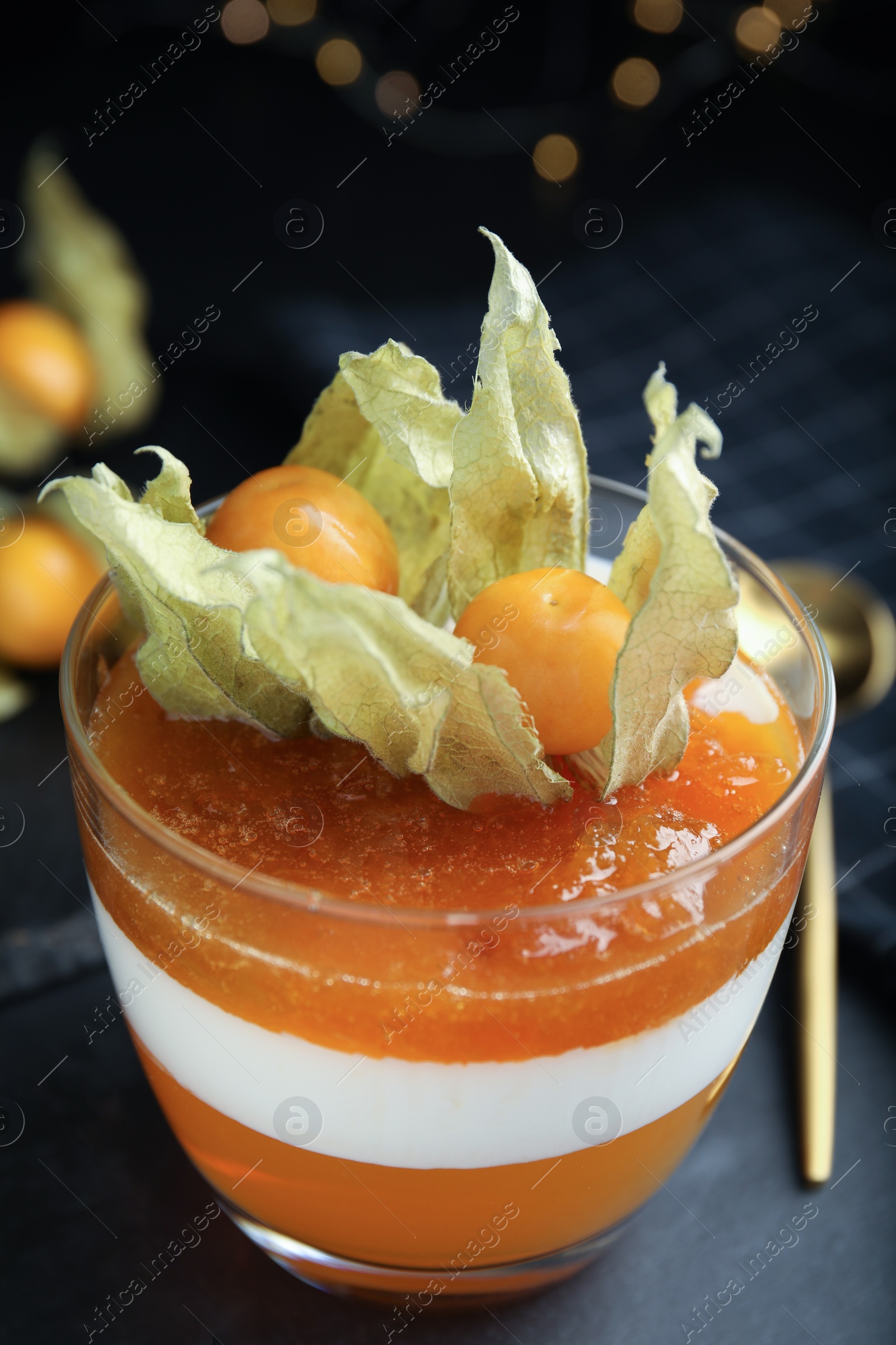 Photo of Delicious dessert decorated with physalis on black table, closeup