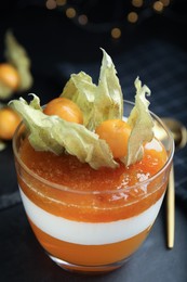 Delicious dessert decorated with physalis on black table, closeup