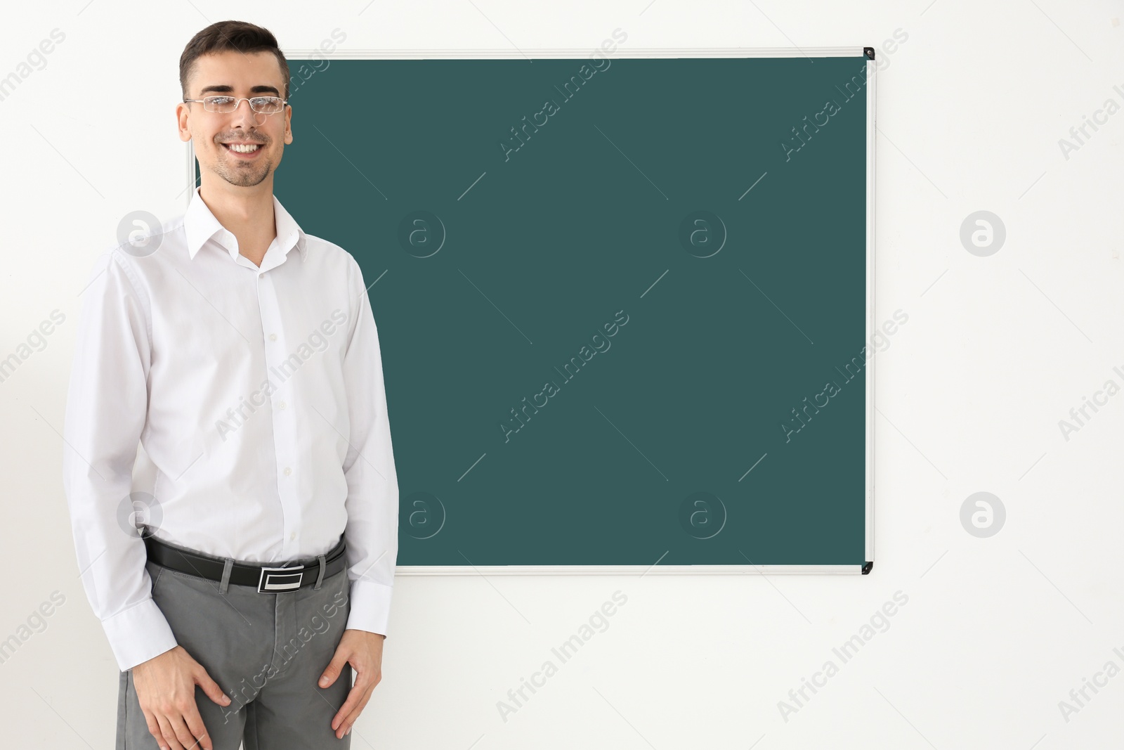 Photo of Young male teacher standing near blackboard on white background