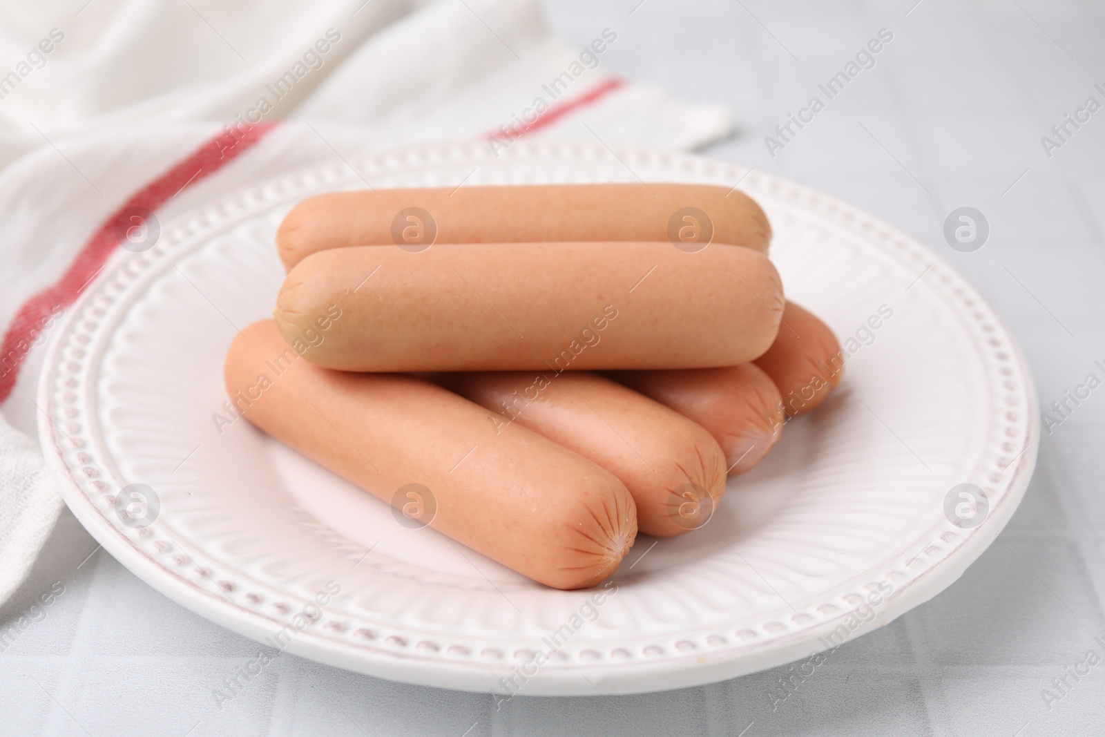 Photo of Delicious boiled sausages on white tiled table, closeup