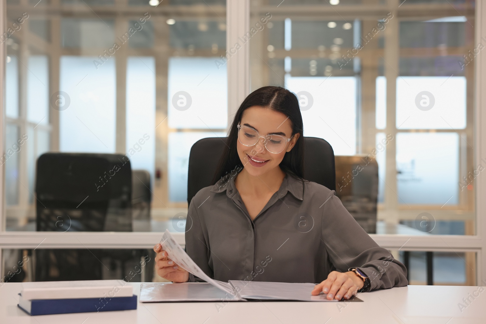 Photo of Smiling woman working at table in office. Lawyer, businesswoman, accountant or manager