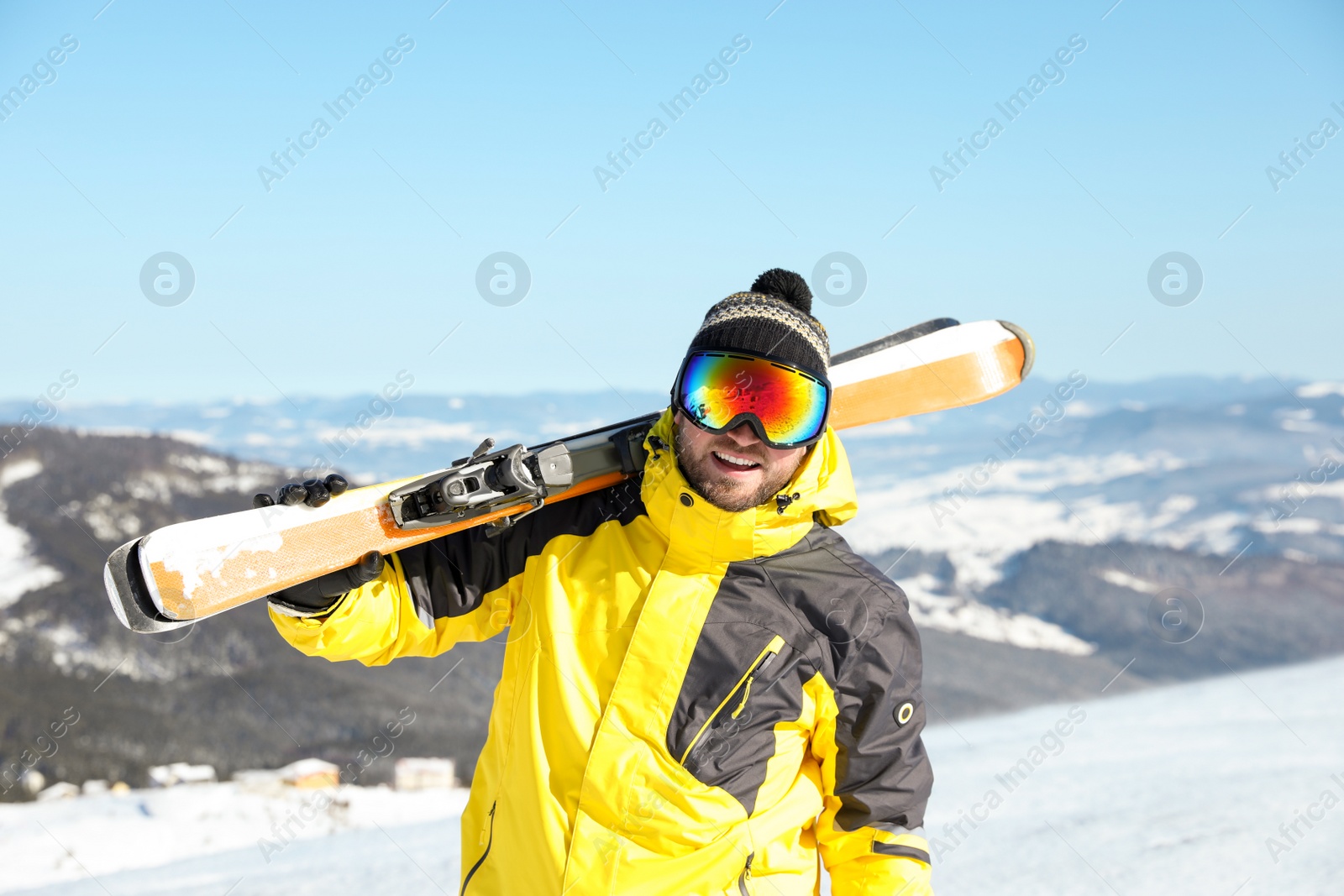 Photo of Happy man with ski equipment in mountains. Winter vacation