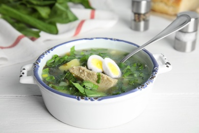 Photo of Delicious sorrel soup with meat and eggs served on white wooden table