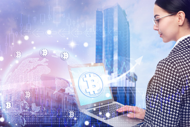 Fintech concept. World globe with bitcoin symbols and businesswoman using laptop on cityscape background