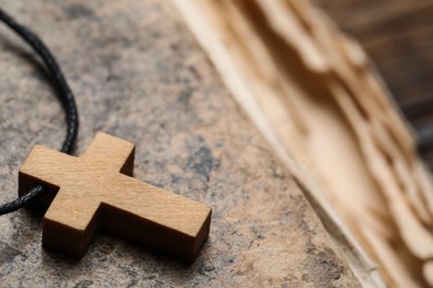 Photo of Wooden Christian cross on old Bible, closeup. Space for text