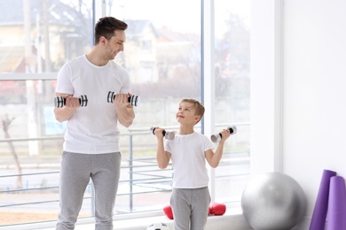 Photo of Dad and his son training with dumbbells in gym