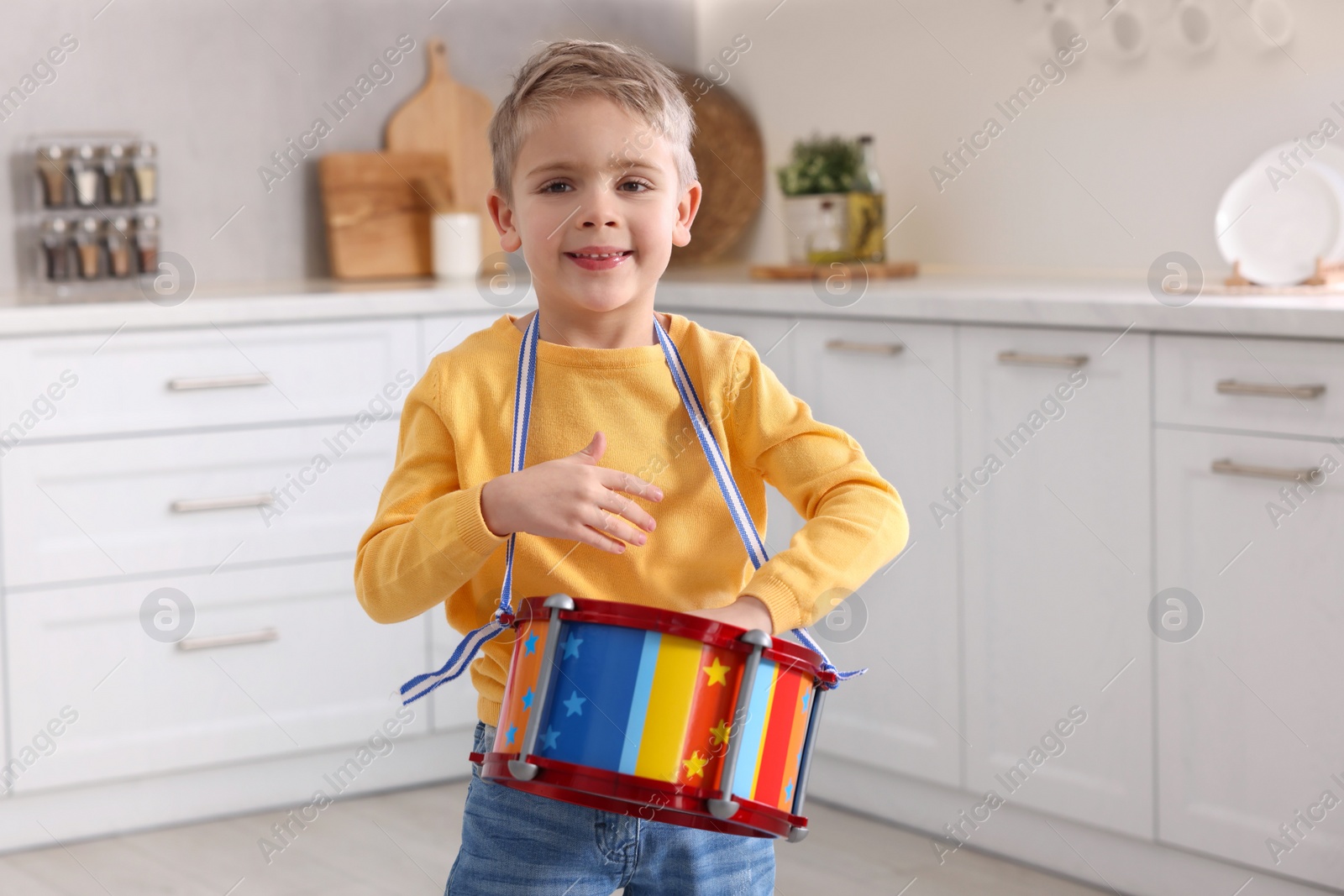 Photo of Little boy playing toy drum in kitchen