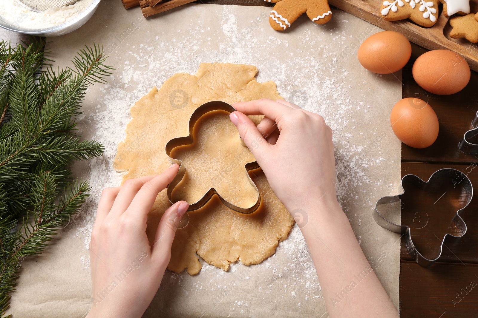 Photo of Woman making Christmas cookies with cutters at wooden table, top view