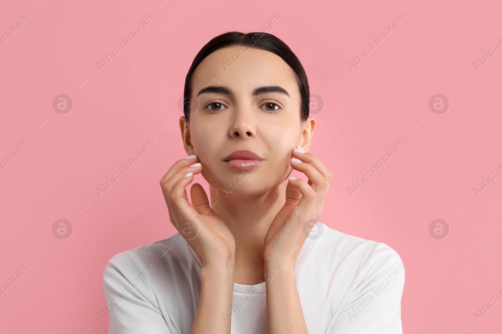 Photo of Woman with dry skin checking her face on pink background