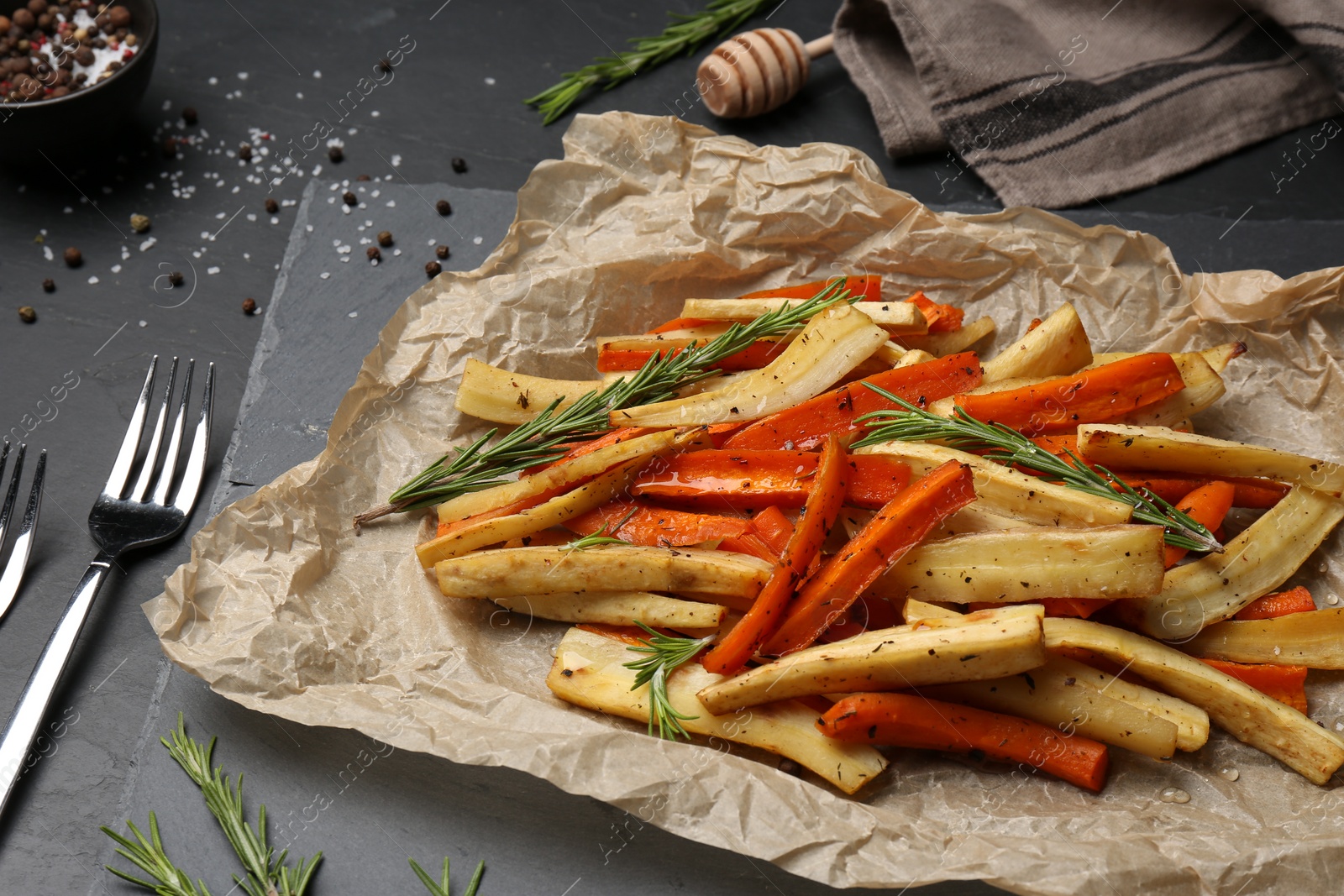 Photo of Tasty baked parsnip and bell pepper served on dark grey table