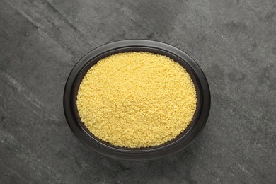 Photo of Bowl of raw couscous on grey table, top view