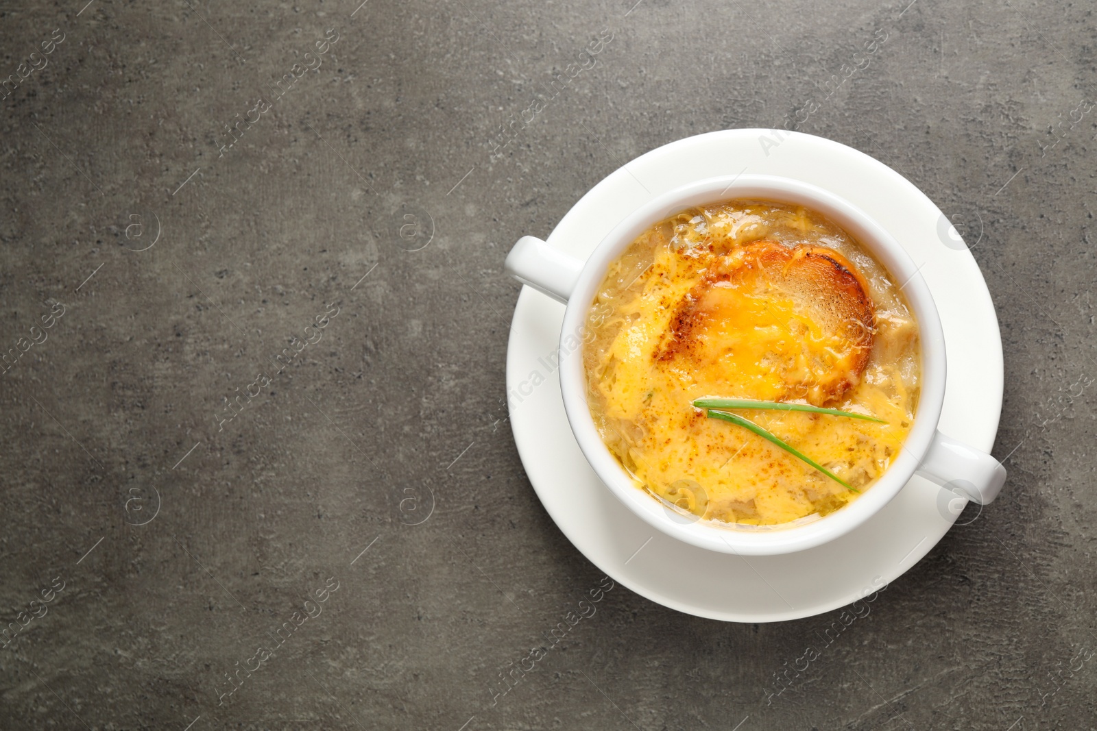 Photo of Tasty homemade french onion soup on grey table, top view. Space for text
