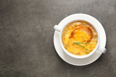 Tasty homemade french onion soup on grey table, top view. Space for text