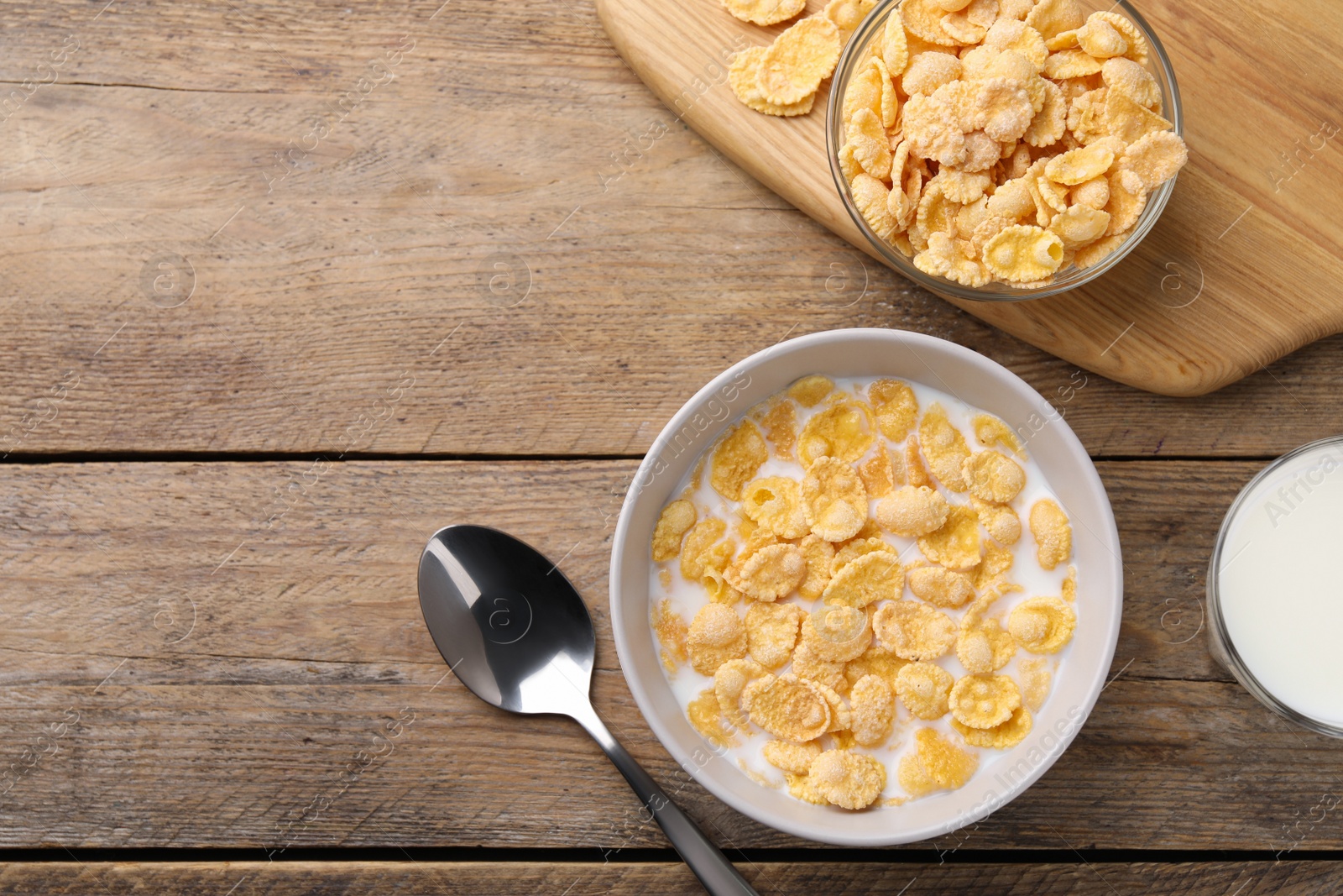 Photo of Tasty cornflakes with milk served on wooden table, flat lay. Space for text