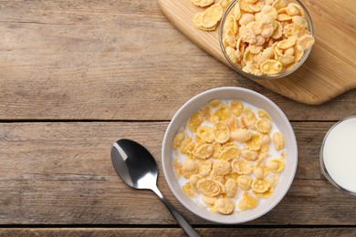 Photo of Tasty cornflakes with milk served on wooden table, flat lay. Space for text