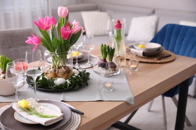 Photo of Beautiful Easter table setting with beautiful flowers in living room
