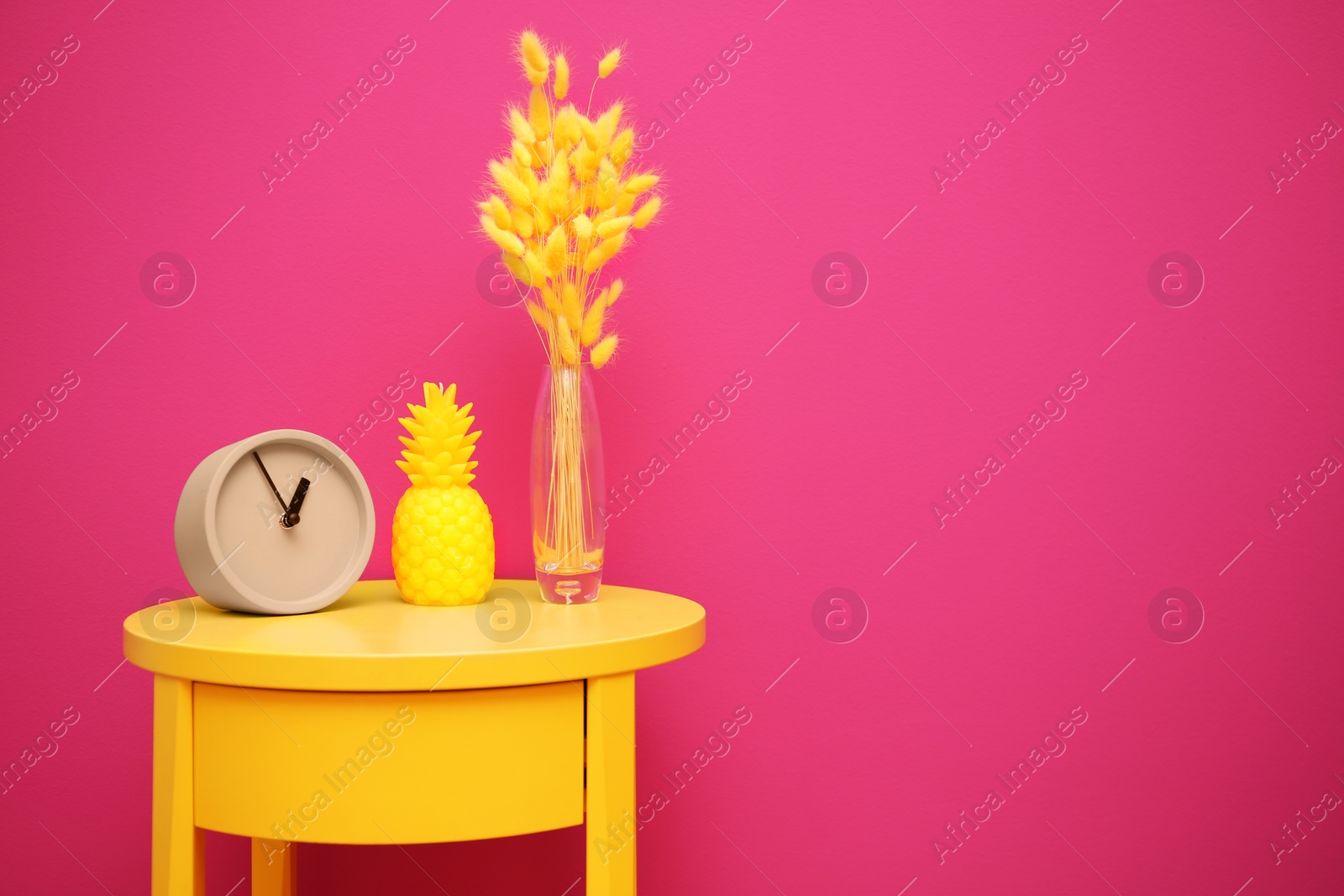 Photo of Stylish pineapple candle on table against color background. Home decorating idea