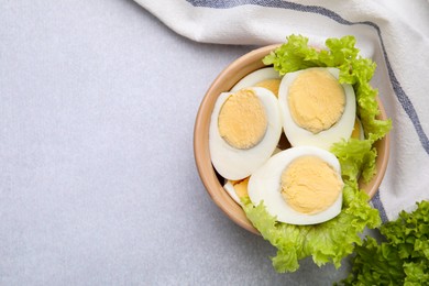 Photo of Fresh hard boiled eggs and lettuce on light grey table, top view. Space for text