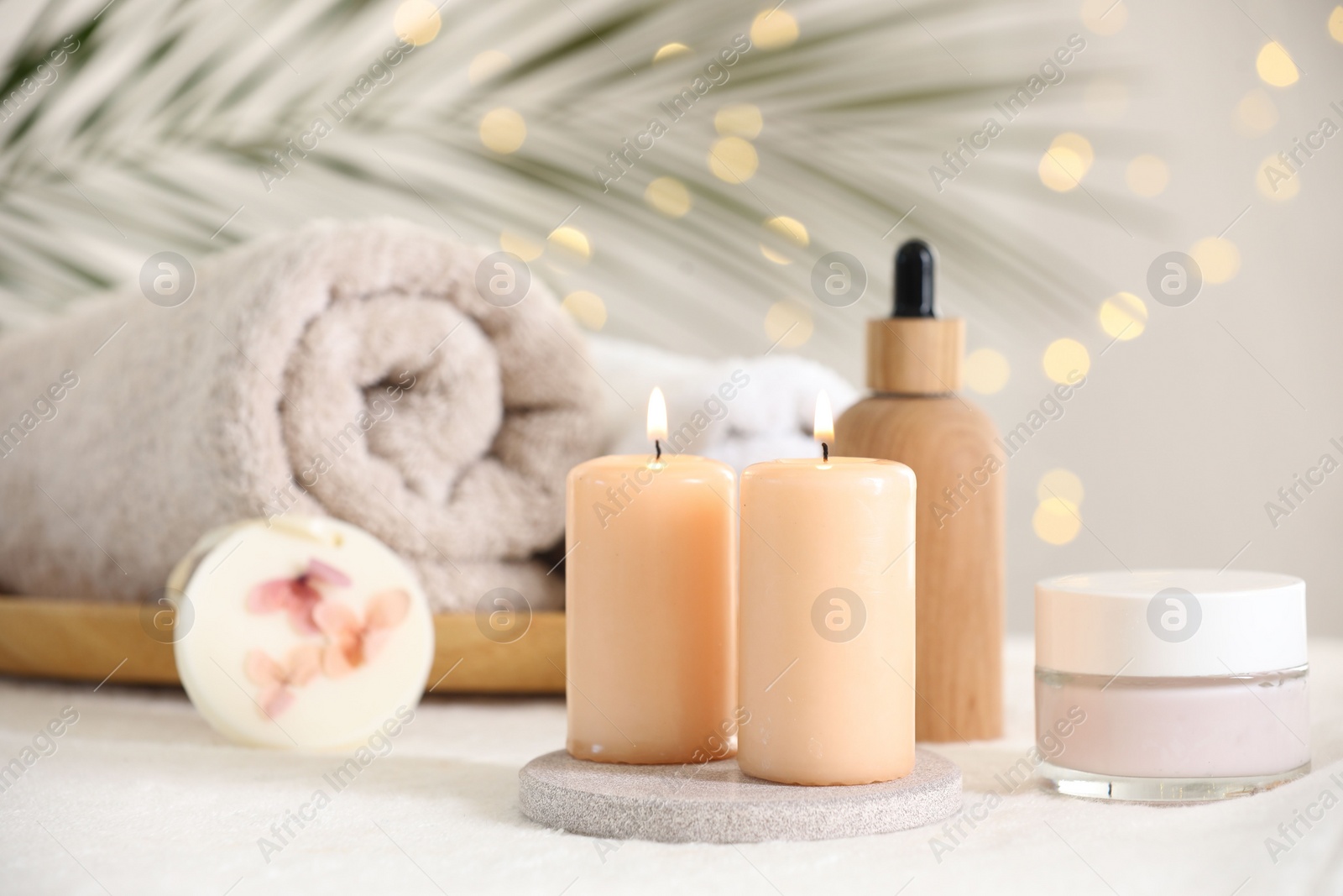 Photo of Spa composition. Burning candles and personal care products on soft white surface