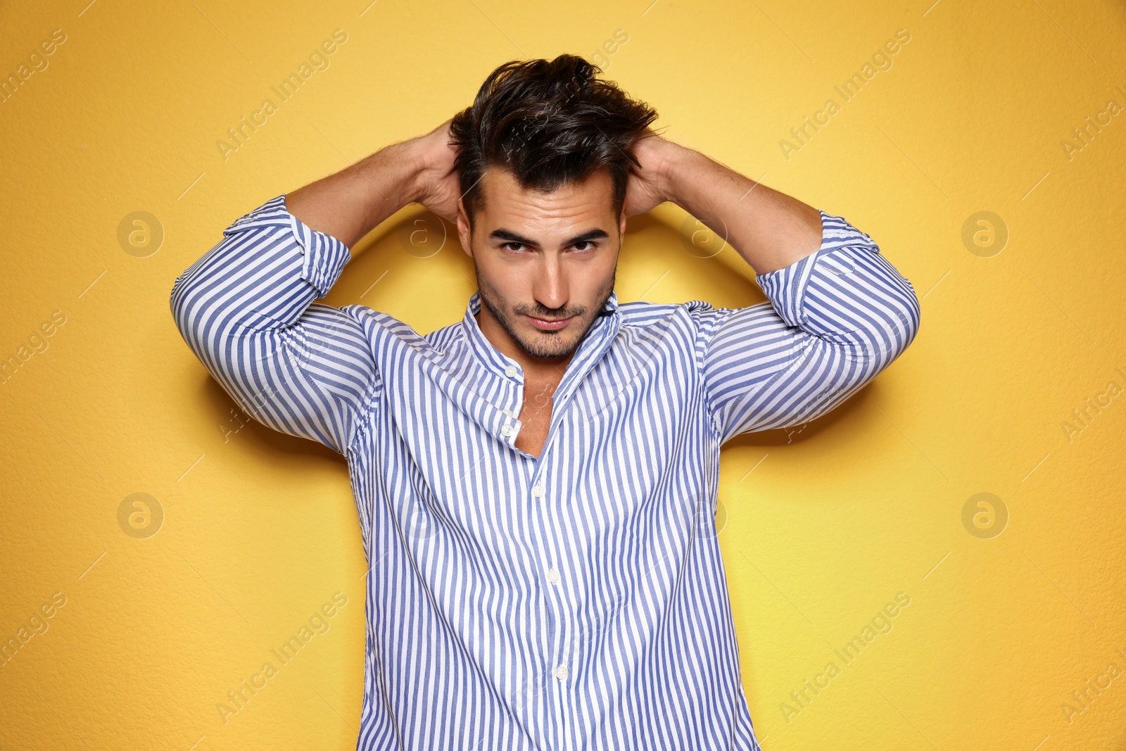 Photo of Young man with trendy hairstyle posing on color background