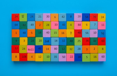 Photo of Wooden cubes with different numbers on light blue background, top view