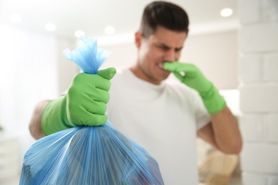 Photo of Man holding full garbage bag at home, focus on hand