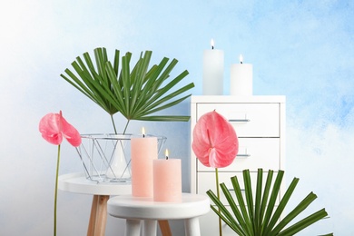Photo of Creative composition with candles and tropical plants indoors