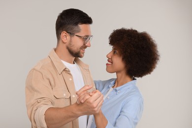 Photo of International dating. Happy couple dancing on light grey background