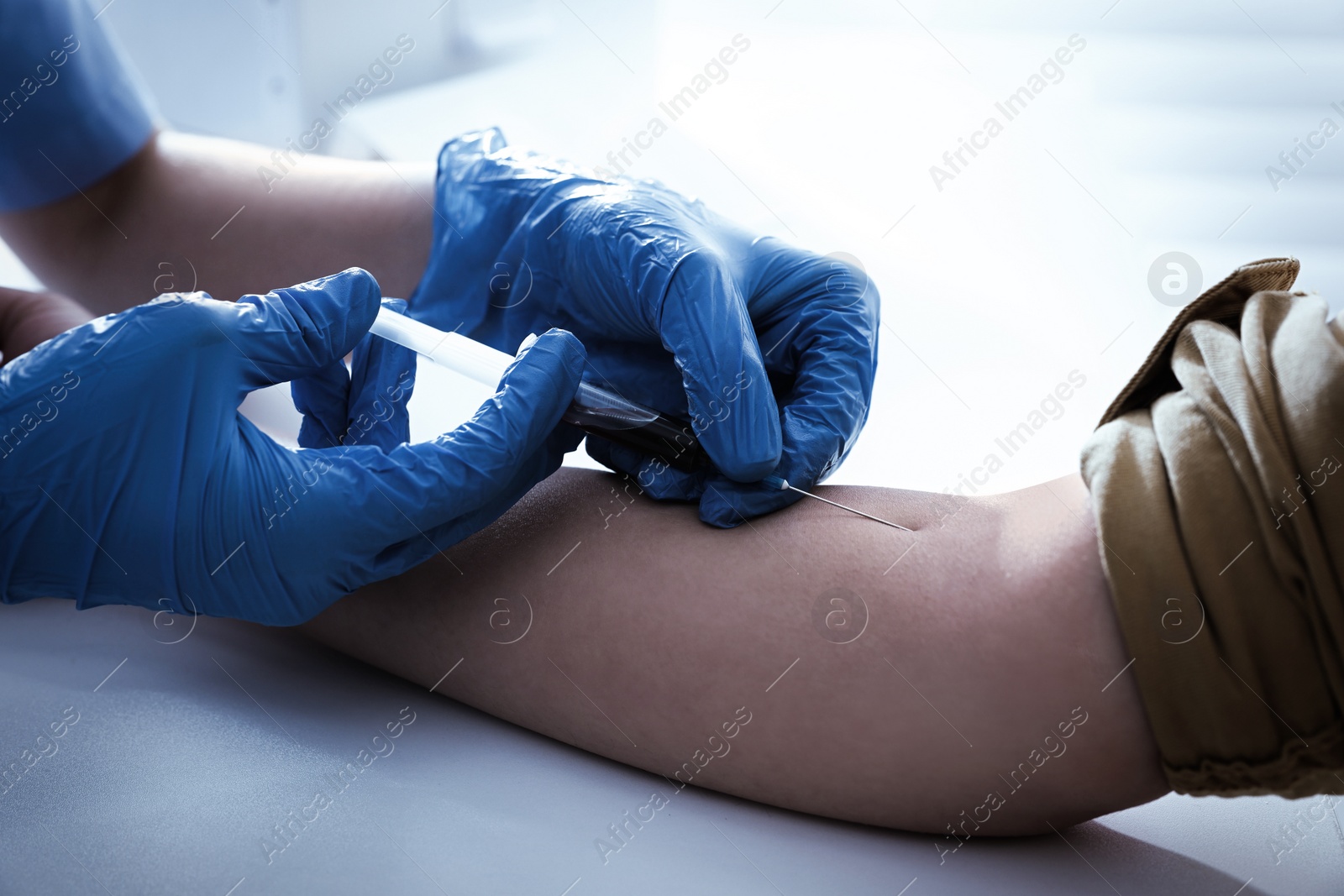 Photo of Doctor drawing blood sample of patient with syringe in hospital, closeup